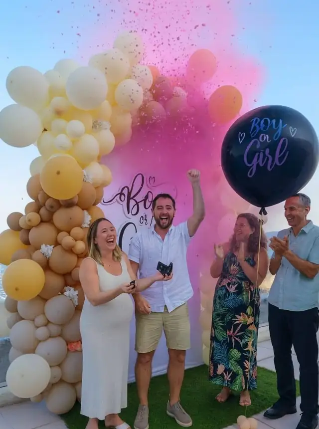 A gender reveal with a balloon arch and confetti