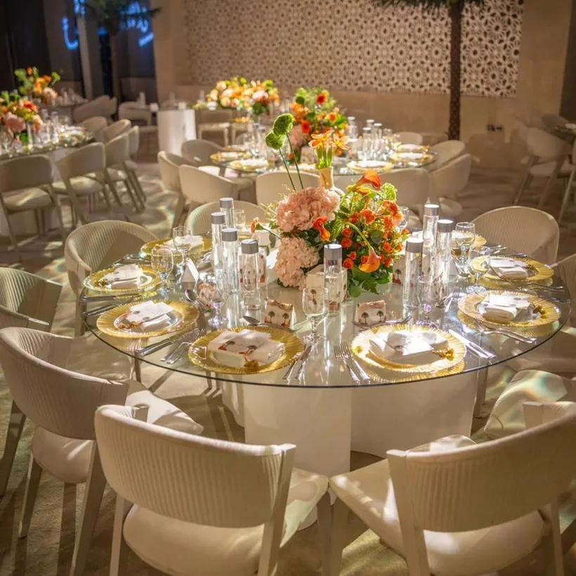 A gala dinner table set with gold chargers and coral florals