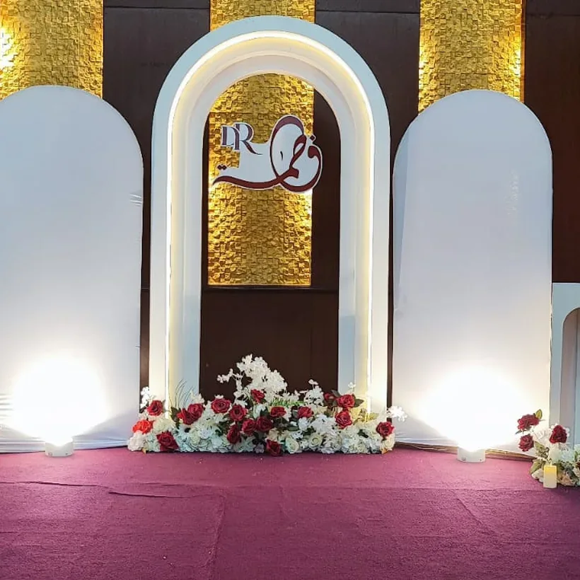 A white arch stage backdrop with red and white roses